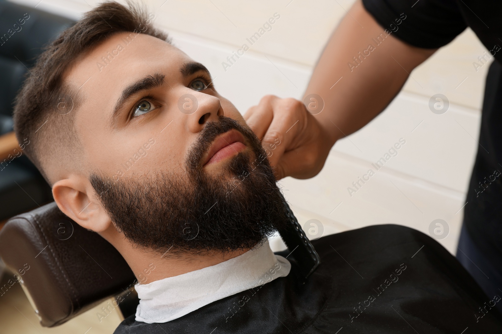 Photo of Professional hairdresser working with client in barbershop, closeup