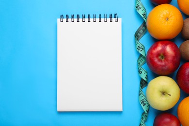 Photo of Notebook, measuring tape and fresh fruits on light blue background, flat lay. Low glycemic index diet