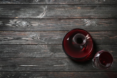 Decanter and glass with red wine on wooden background, top view