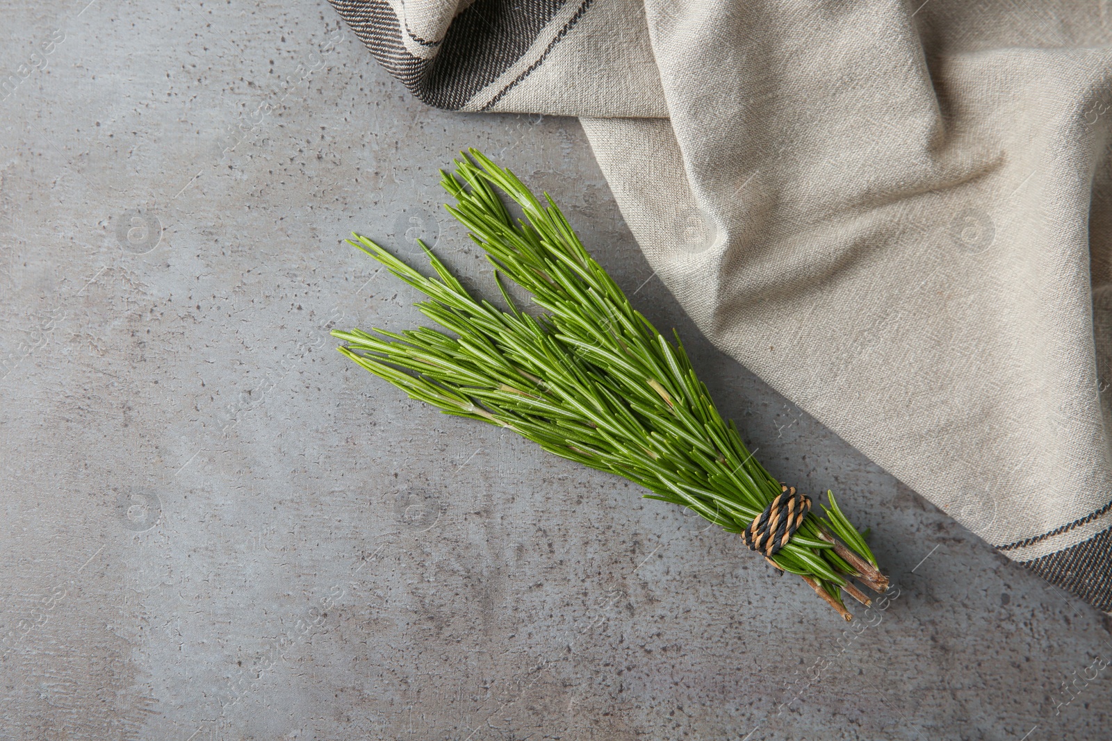 Photo of Bundle of fresh rosemary and napkin on grey background, flat lay. Space for text