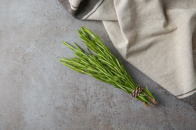 Photo of Bundle of fresh rosemary and napkin on grey background, flat lay. Space for text