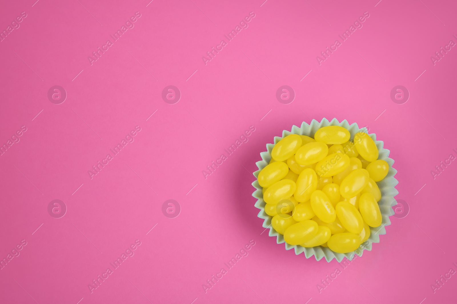 Photo of Delicious lemon drops on pink background, top view. Space for text