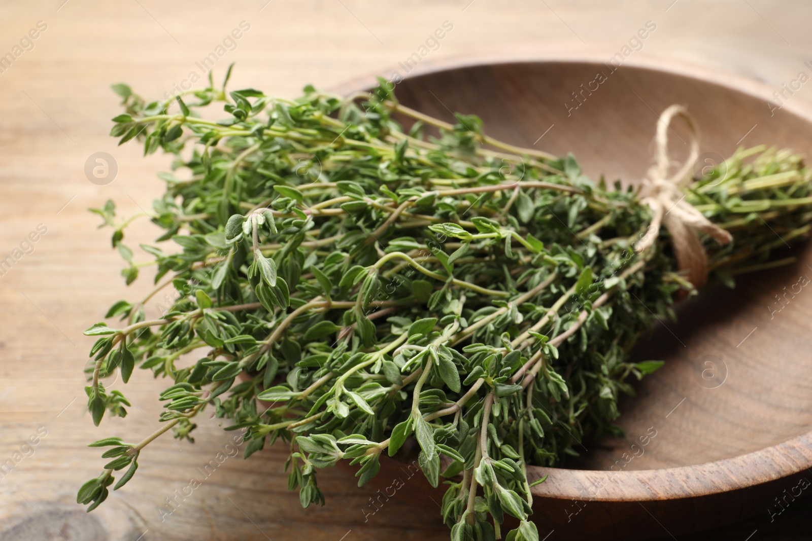 Photo of Bunch of aromatic thyme on wooden table, closeup