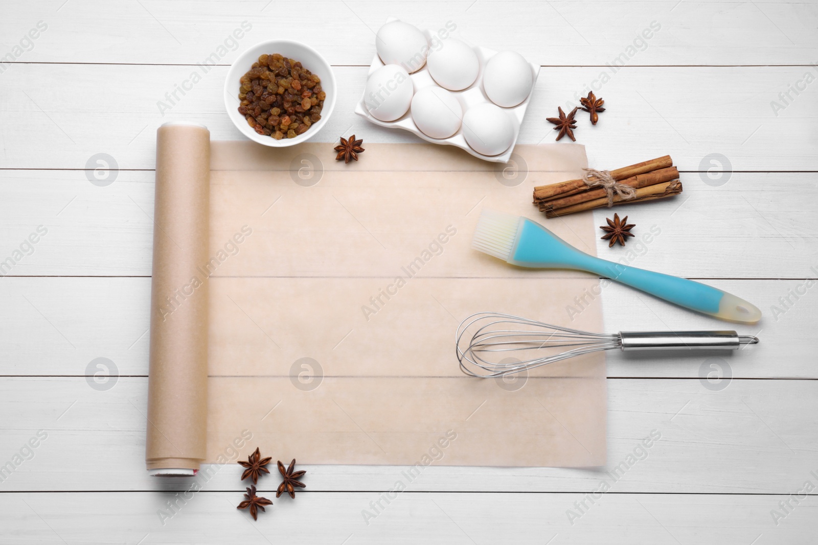 Photo of Baking parchment paper and different ingredients on white wooden table, flat lay. Space for text