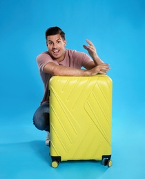 Photo of Excited man with suitcase for summer trip on blue background. Vacation travel