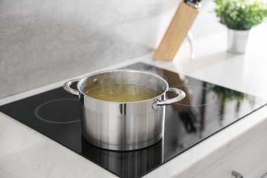 Pot with delicious soup on cooktop in kitchen