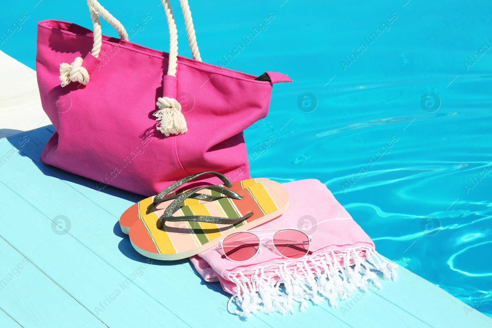 Photo of Beach accessories on wooden deck near swimming pool. Space for text