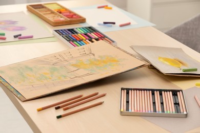Photo of Artist's workplace with drawings, soft pastels and color pencils on table