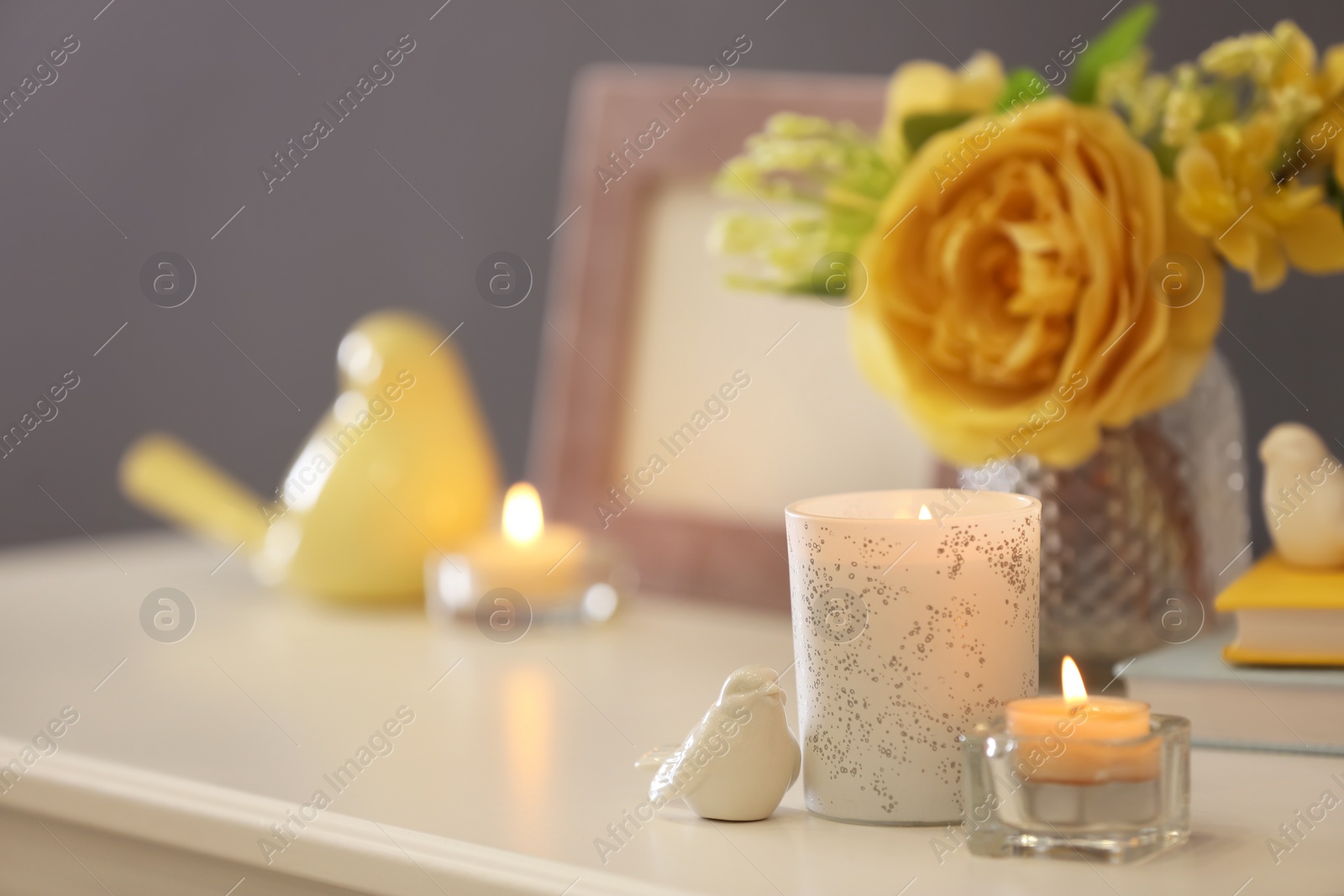 Photo of Beautiful burning candles, decor and flowers on table at home