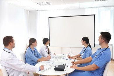 Photo of Team of doctors using video projector during conference indoors