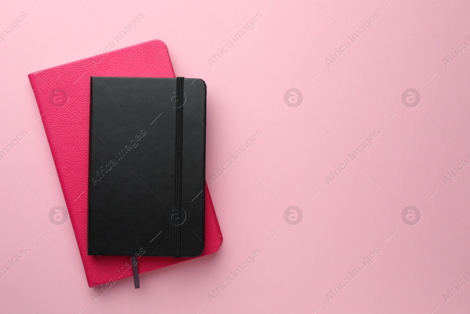 Photo of Different notebooks on light pink background, top view. Space for text