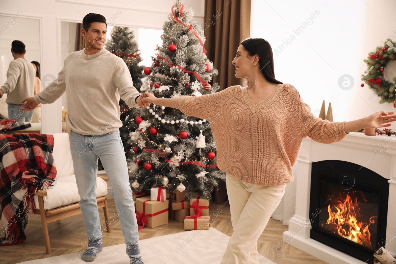 Photo of Happy couple dancing near Christmas tree at home