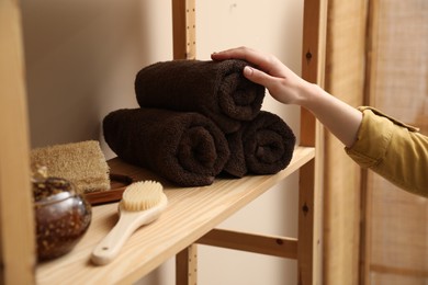 Photo of Woman taking rolled towel from shelf indoors, closeup