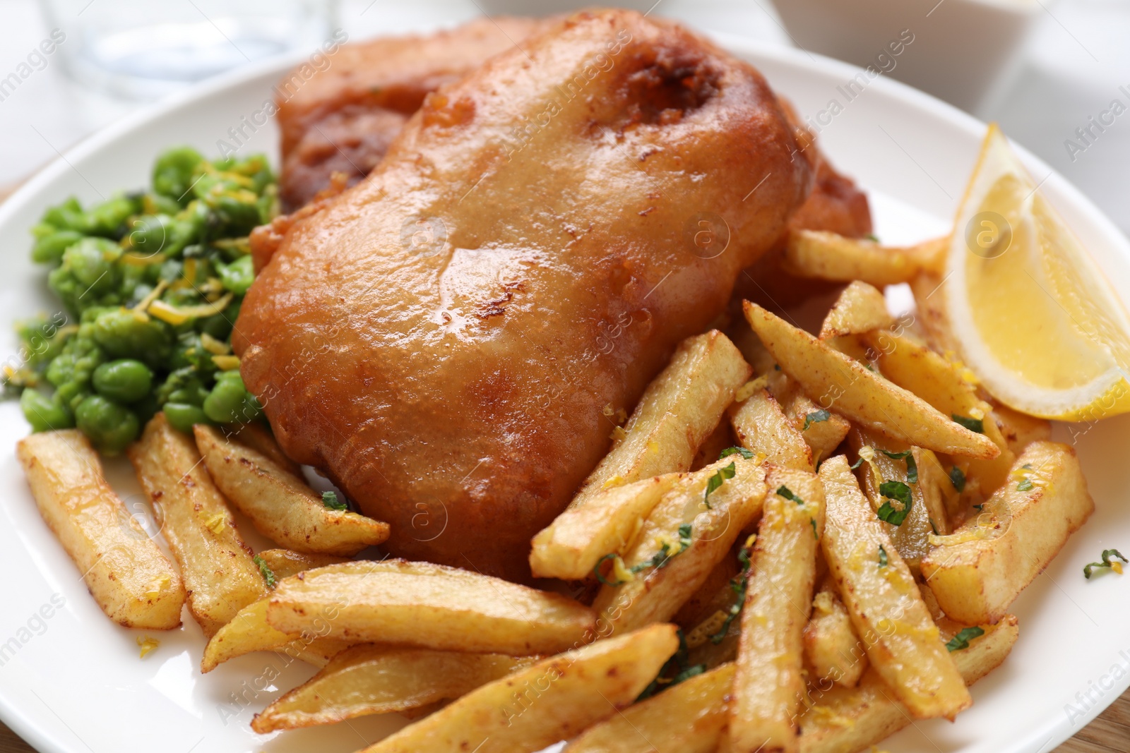 Photo of Tasty fish, chips, peas and lemon on table, closeup