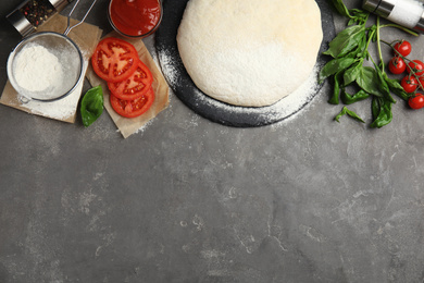 Photo of Flat lay composition with dough and fresh ingredients on grey table, space for text. Pizza recipe