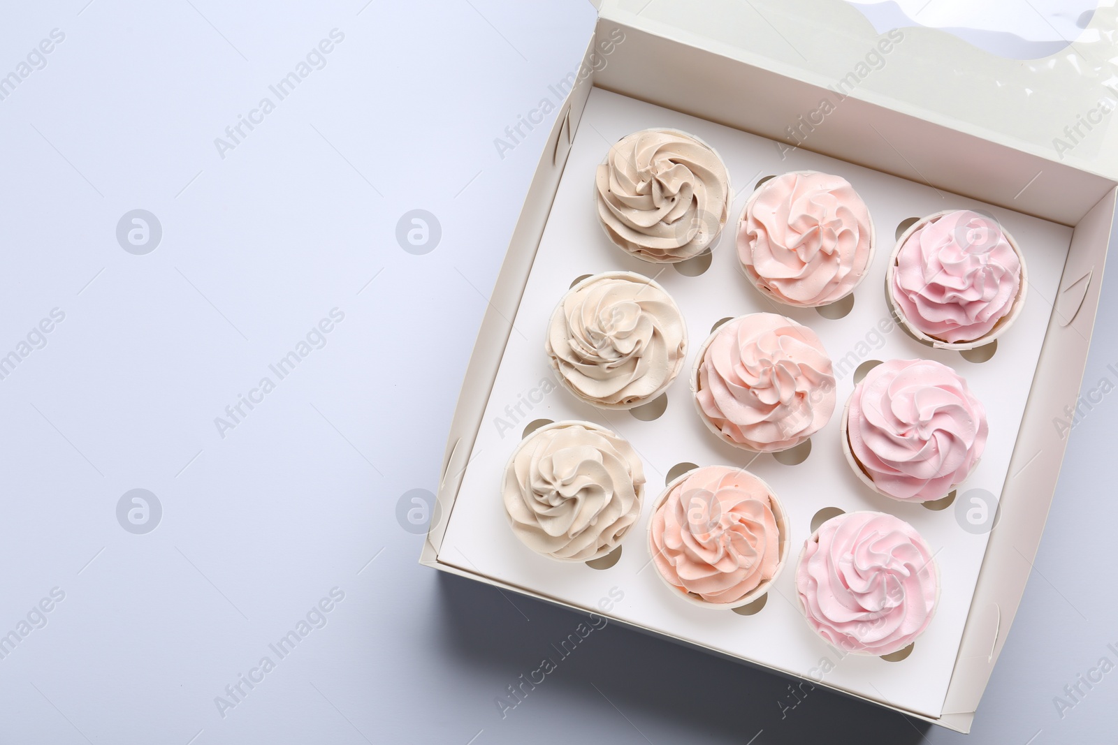 Photo of Tasty cupcakes in box on white background, top view. Space for text