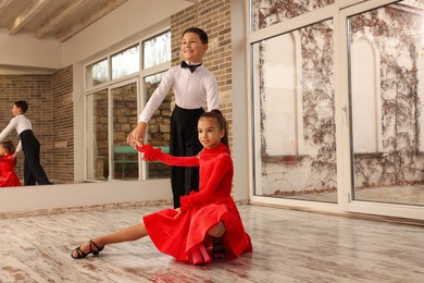 Beautifully dressed couple of kids dancing together in studio