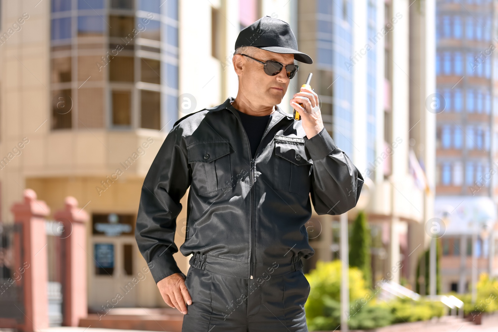 Photo of Male security guard using portable radio transmitter outdoors