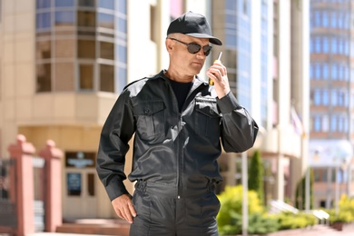 Male security guard using portable radio transmitter outdoors