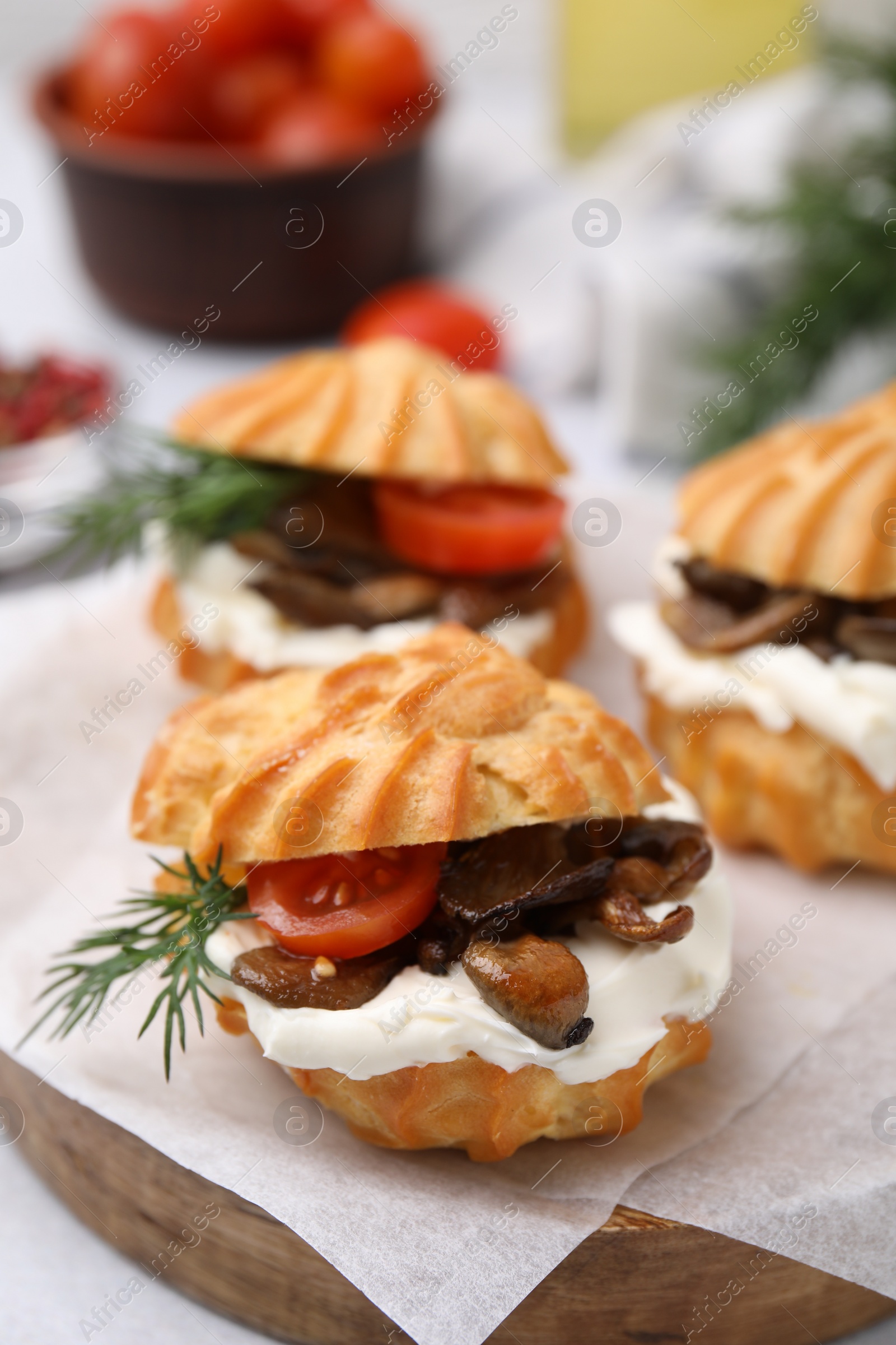 Photo of Delicious profiteroles with cream cheese, mushrooms, tomato and dill on board, closeup