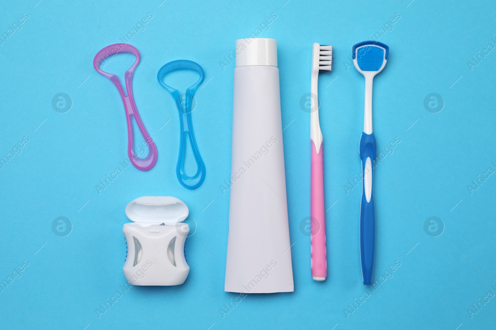 Photo of Flat lay composition with tongue cleaners and teeth care products on light blue background