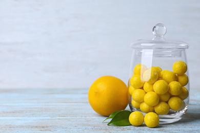 Photo of Fresh lemon and tasty chewing gums on light blue wooden table, space for text