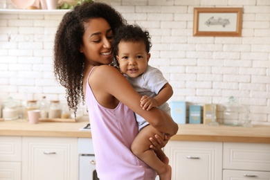 African-American woman with her baby in kitchen. Happiness of motherhood