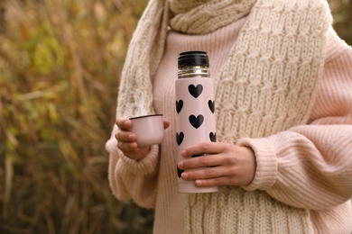 Photo of Woman with beautiful pink thermos outdoors, closeup