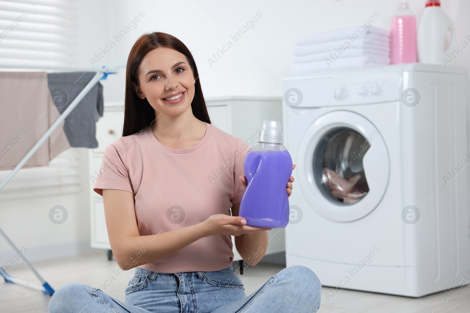 Photo of Woman holding fabric softener in bathroom, space for text