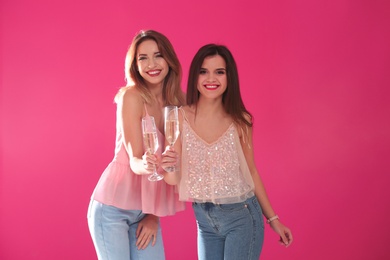 Portrait of happy friends with champagne in glasses on color background