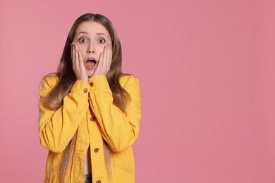 Portrait of shocked teenage girl on pink background. Space for text