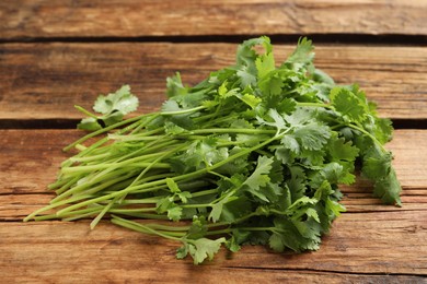 Photo of Bunch of fresh aromatic cilantro on wooden table
