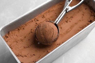 Photo of Scoop of chocolate ice cream in container on table, closeup