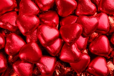 Heart shaped chocolate candies as background, top view