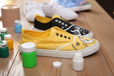 Photo of Amazing customized shoes and painting supplies on wooden table