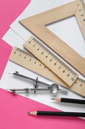 Photo of Different rulers, protractor and compass on pink background, flat lay
