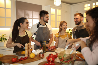 Photo of Happy people cooking food together in kitchen
