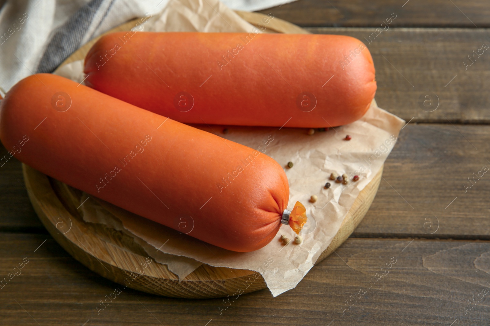 Photo of Board with tasty boiled sausages on wooden table, closeup