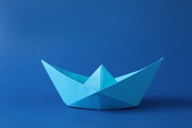 Handmade paper boat on blue background. Origami art