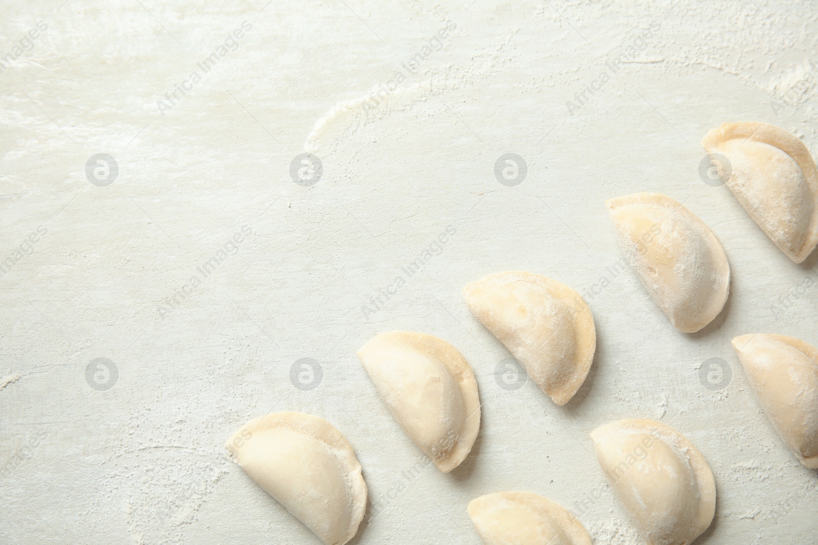 Photo of Raw dumplings on light background, top view with space for text. Process of cooking