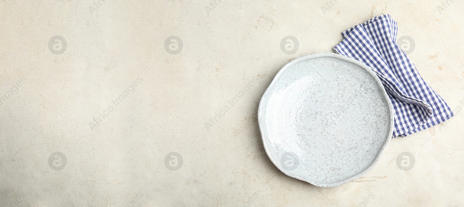 Photo of Empty plate and napkin on light table, top view