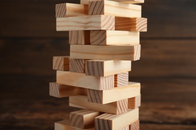 Photo of Jenga tower made of wooden blocks on table, closeup