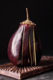 Photo of Cut purple eggplant on black slate table, closeup