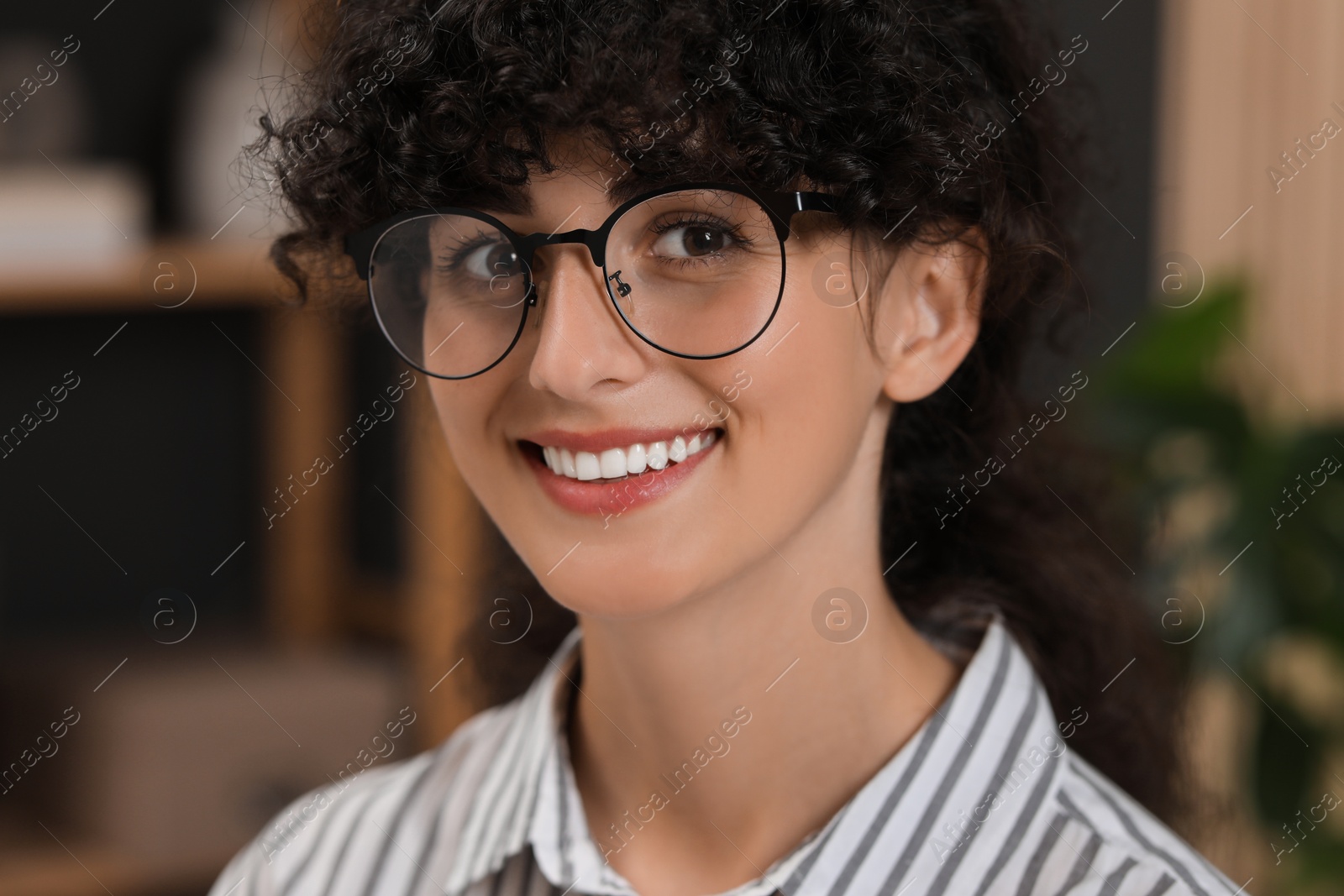 Photo of Portrait of beautiful woman with curly hair indoors. Attractive lady smiling and looking into camera