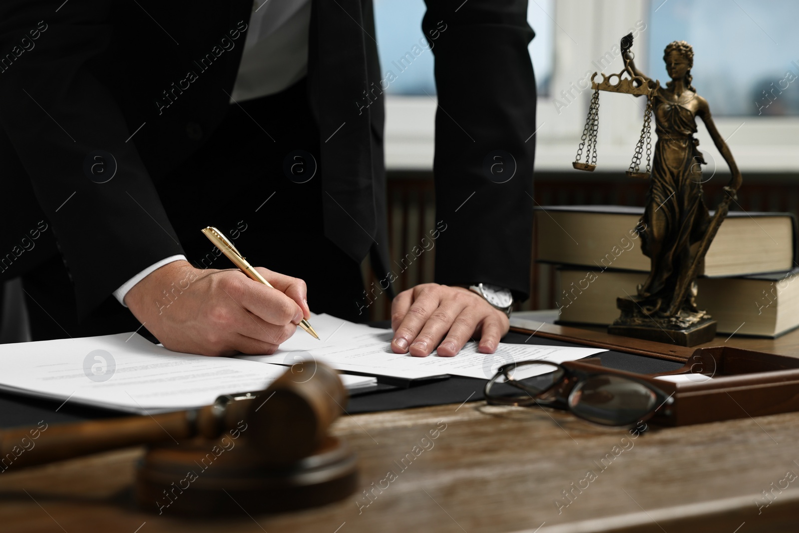 Photo of Lawyer working with documents at wooden table in office, closeup