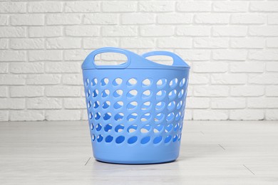 Empty laundry basket near white brick wall