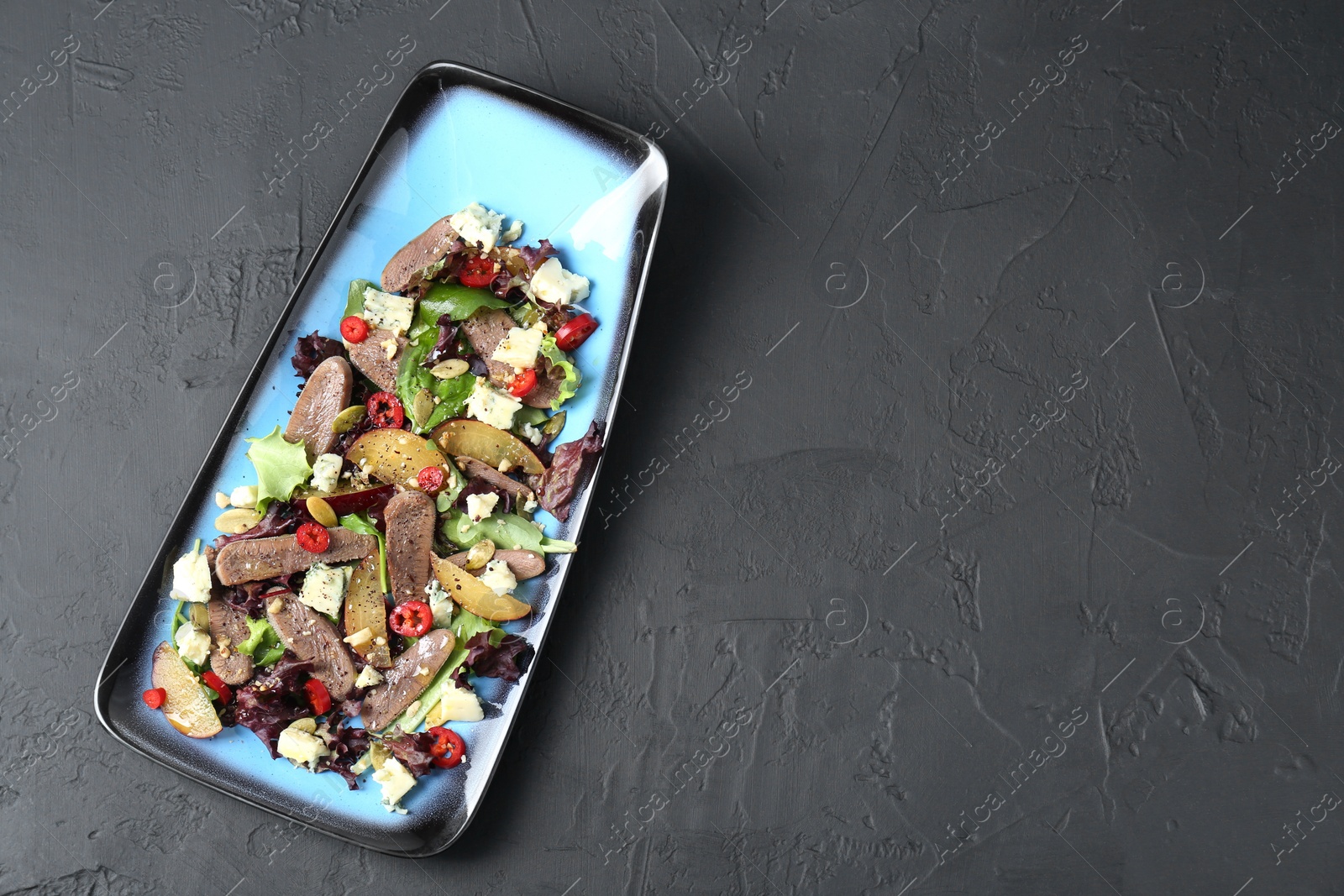 Photo of Delicious salad with beef tongue and cheese on black textured table, top view. Space for text