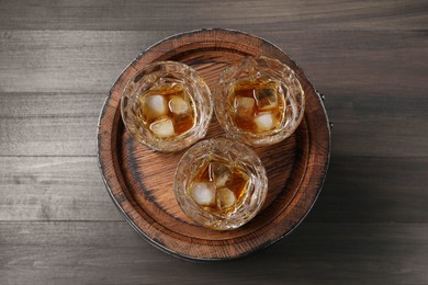 Photo of Barrel and glasses of tasty whiskey on wooden table, top view