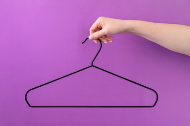 Photo of Woman holding hanger on purple background, closeup