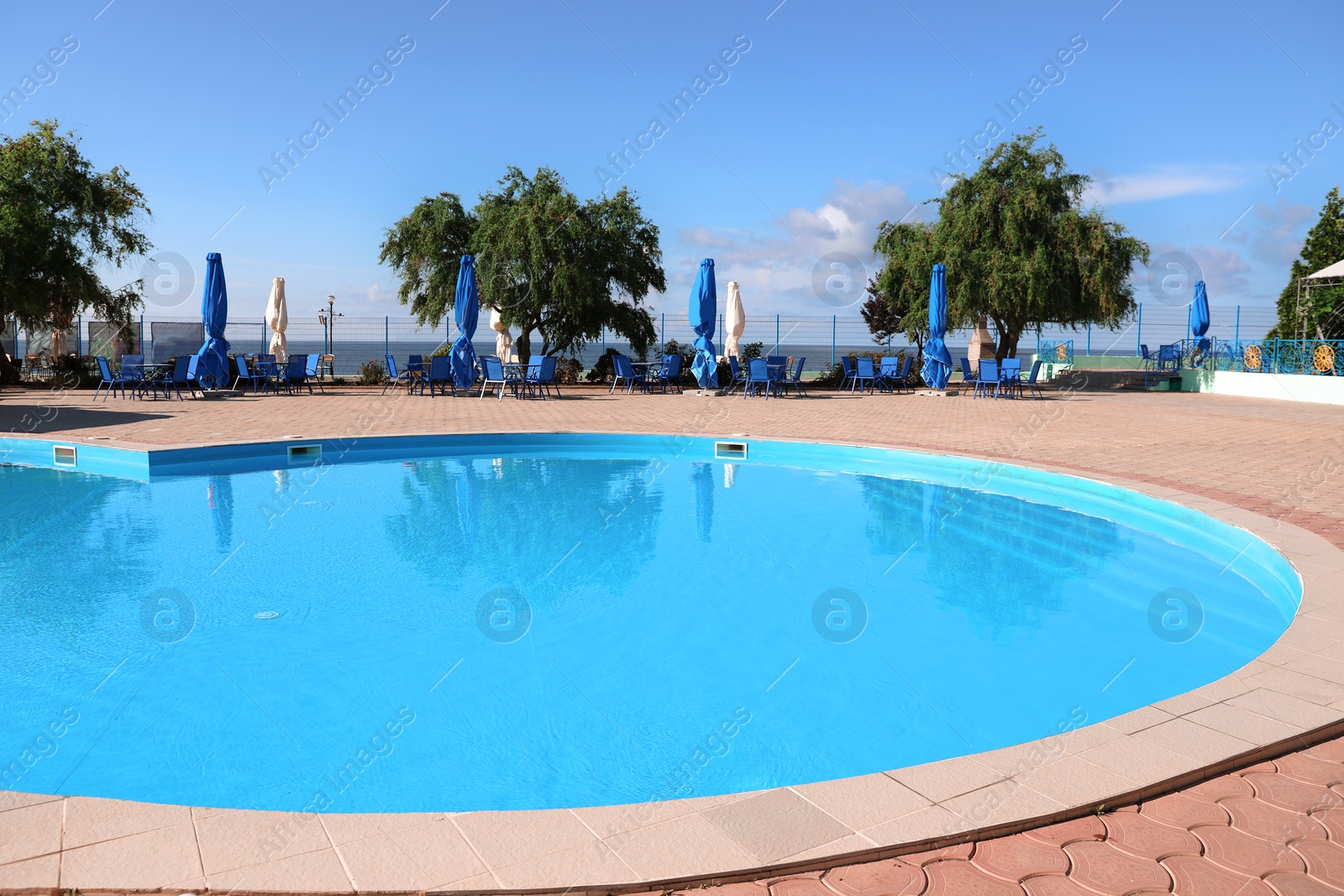 Photo of Outdoor swimming pool with clear water on sunny day. Summer vacation